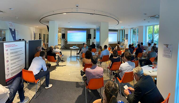 5tes Thalkirchner Gelenksymposium 2021 3 Dr Bigdeli Chefarzt der Radiologie hält einen Vortrag vor Publikum mit Blick in das Foyer des Artemed Klinikum München Süd