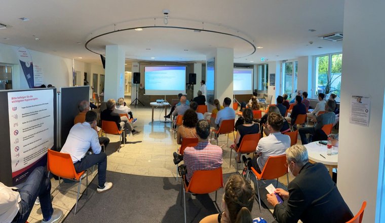 5tes Thalkirchner Gelenksymposium 2021 3 Dr Bigdeli Chefarzt der Radiologie hält einen Vortrag vor Publikum mit Blick in das Foyer des Artemed Klinikum München Süd