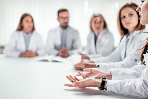 Weißer Tisch mit Ärzten in einer Diskussionsrunde - Hintergrundbild