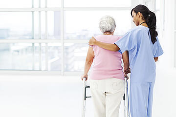 Foto Krankenpflegerin hilft älteren Patientin beim gehen mit einer Gehhilfe