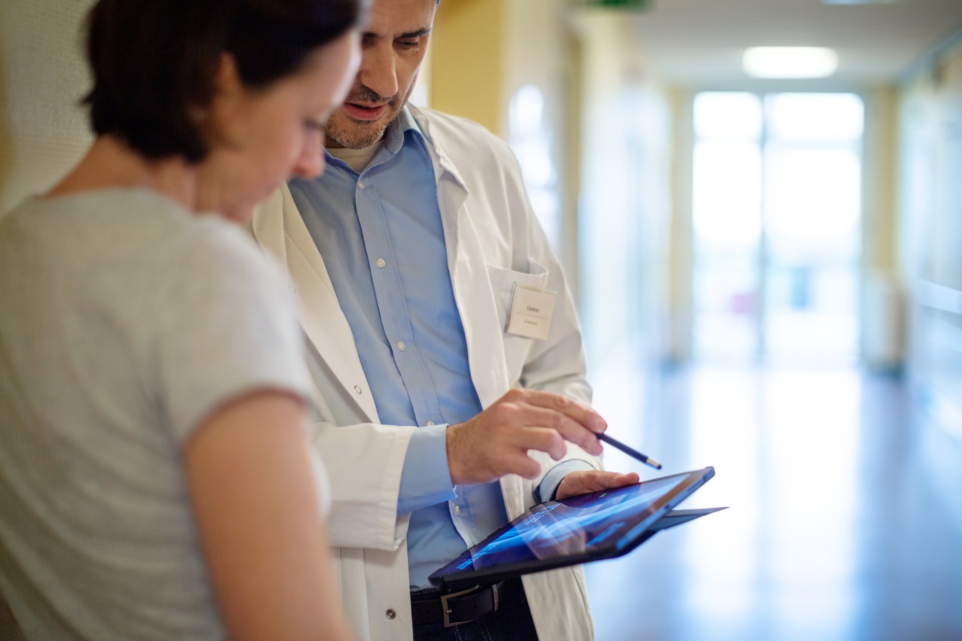Hintergrundbild Arzt mit Patientin im Gespräch auf einem Gang